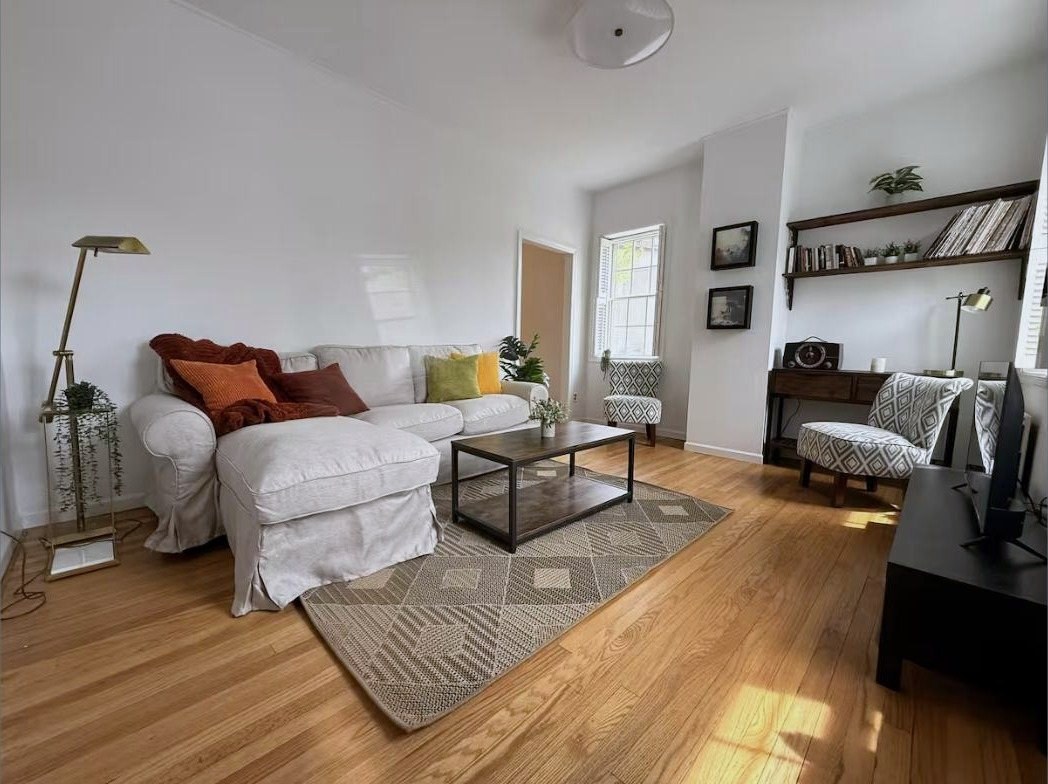 Living room with slipcovered sofa, wood floors, and built-in shelving