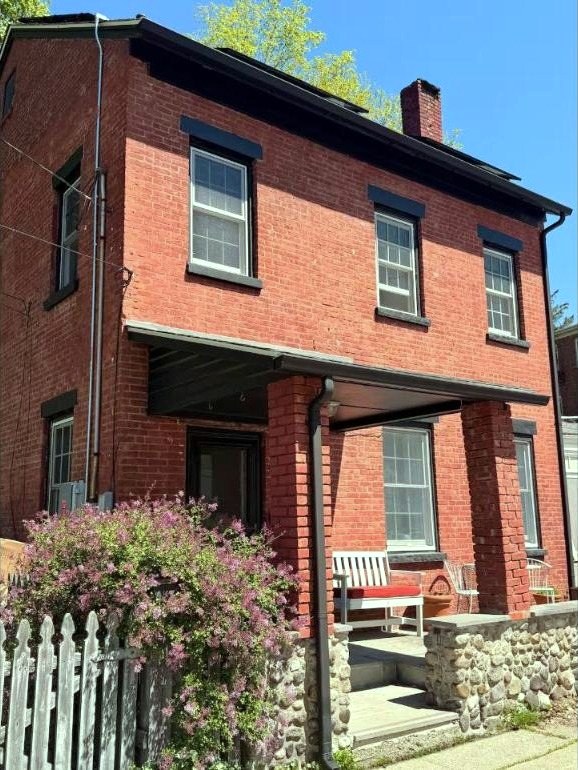 Red brick facade of 6 Church Street, Cold Spring NY, with a garden and a porch