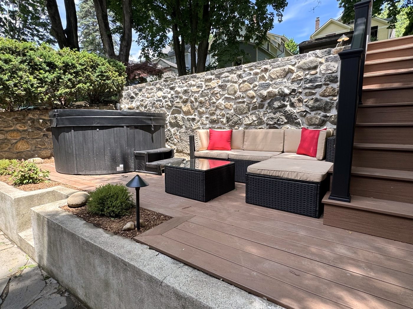 Covered hot tub on the stone patio beside a cushioned outdoor lounge area