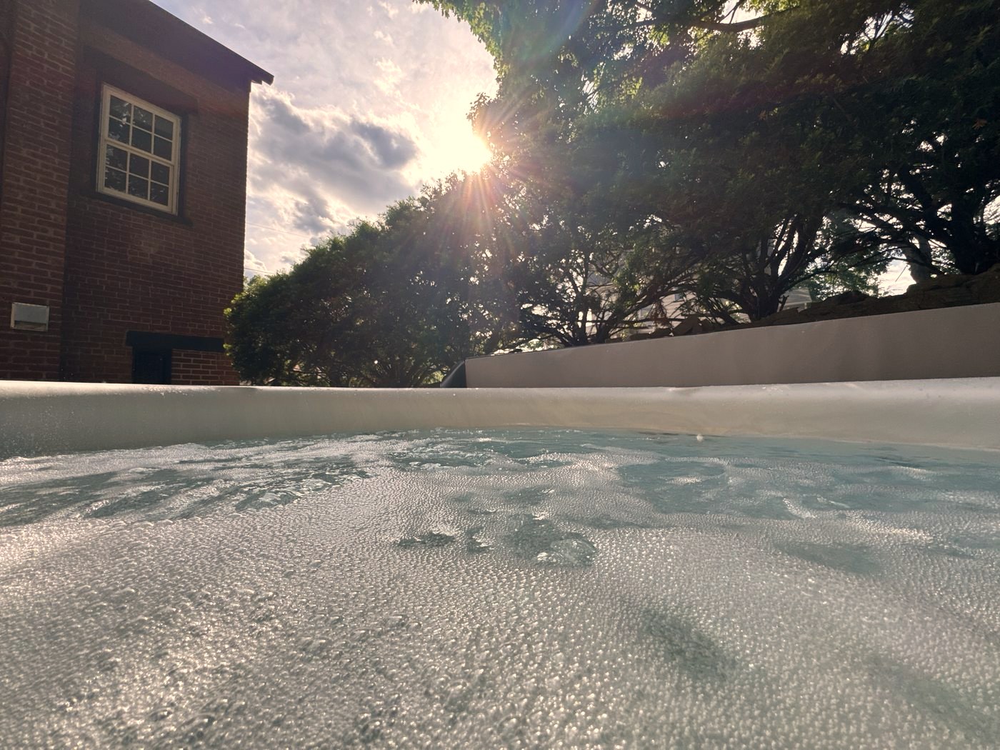 Hot tub running with the brick house and trees behind